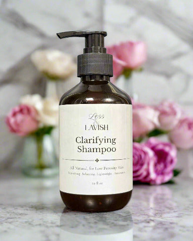 Amber pump bottle of Less & Lavish Feminine Clarifying Shampoo with white label, designed for deep‑cleansing hair and balancing scalp health.