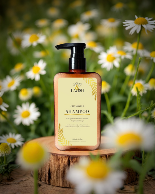 Less & Lavish Chamomile Shampoo bottle on a wooden stand with daisies in the background
