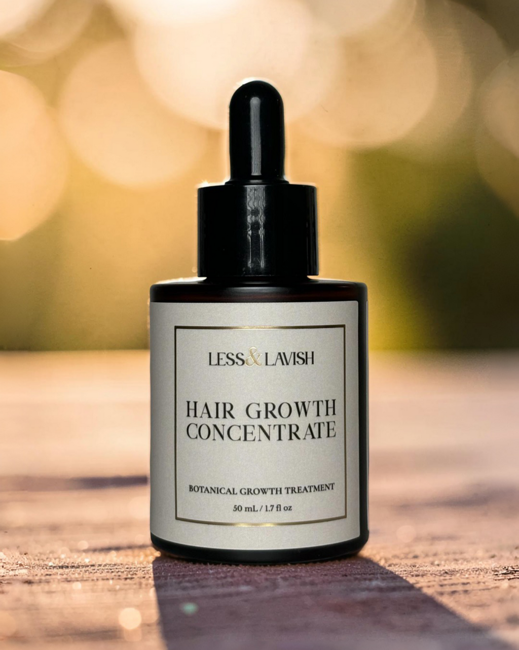 Less & Lavish Hair growth concentrate bottle on a wooden surface with a blurred natural background