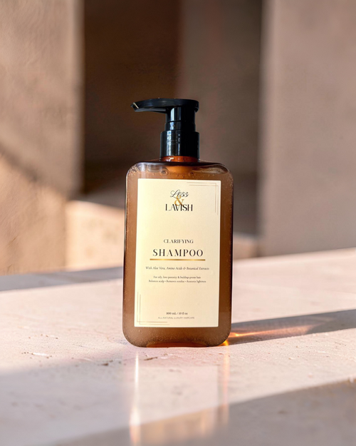 Less & Lavish clarifying shampoo bottle on a marble surface with a neutral background